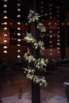 Colorful artificial flower garlands hanging from ceiling at event venue with floral greenery installation and dramatic lighting – ShopWildThings.com