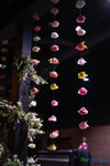 Colorful artificial flower garlands hanging from ceiling at event venue with floral greenery installation and dramatic lighting – ShopWildThings.com