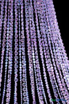 Macro detail of iridescent diamond crystal bead strands on Belvedere chandelier reflecting purple and blue event lighting