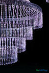 Macro detail of iridescent diamond crystal bead strands on Belvedere chandelier reflecting purple and blue event lighting