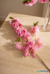 Pink artificial cherry blossom branch detail on travertine tabletop with clear vase, ShopWildThings.com floral decor