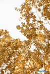 Close up of metallic gold leaves on 7 foot artificial weeping tree, professional event decor detail showing realistic shimmer and branch structure