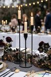 Matte black long stem taper candle holders with lit candles styled as elegant centerpiece for wedding reception table decor