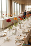 Artificial Real Feel poppy stems in red, yellow-orange, and orange arranged in minimalist vases on a luxury wedding reception table with elegant place settings and soft natural light