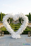 White heart shaped floral arch outdoor setup silk rose wedding backdrop elegant event decor ShopWildThings.com