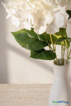 Close-up of white artificial hydrangea flowers with realistic green leaves and stems in white vase for ShopWildThings.com