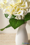 Detailed view of cream white faux hydrangea flowers, textured green leaves, and white vase for ShopWildThings.com