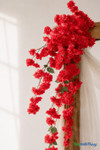 41" Red Cascading "Spring Blossom" Spray – Extra-Full Silk Floral Waterfall from ShopWildThings.com styled on a wooden wedding arch with soft white draping, shown in a close-up detail view with rich red blooms and trailing floral sprays.