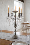 18.75" Silver Metal Candelabra Centerpiece with five lit taper candles and hanging glass crystal strands displayed on an elegant dining table from ShopWildThings.com.