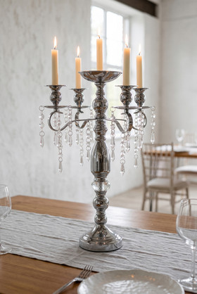 18.75" Silver Metal Candelabra Centerpiece with five lit taper candles and hanging glass crystal strands displayed on an elegant dining table from ShopWildThings.com.