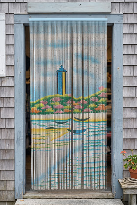 Painted Bamboo Beaded Curtain displayed in a coastal storefront doorway with the lighthouse artwork visible from ShopWildThings.com.