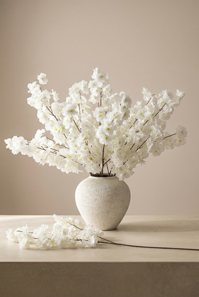 ShopWildThings Artificial Silk Dogwood Branch off-white arrangement in ceramic vase with additional branch styled on tabletop in warm interior