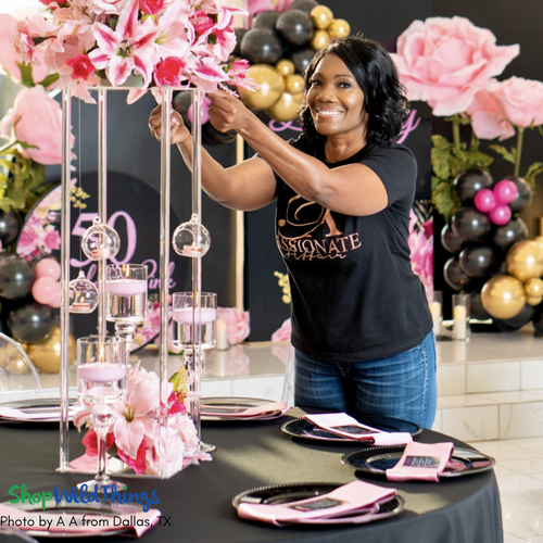 Elevate your tablescape with modern Clear Centerpiece and Floral Risers by ShopWildThings.com! Featured in this image is a black, pink, and gold 50th birthday party tablescape with beautiful pink lily flower arrangements, hanging candles, and floating candles working together to create a beautiful table centerpiece.