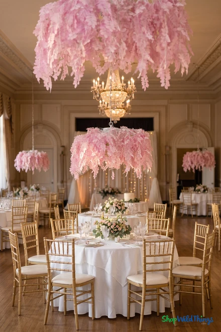 Pink acacia leaf floral chandelier canopy hanging over wedding reception tables with gold chiavari chairs in elegant ballroom, ShopWildThings.com
