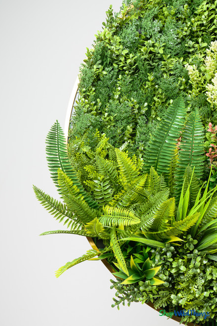 Close-up of ShopWildThings Foliage Fusion Ring Garden showing vibrant artificial plants and greenery textures inside the gold frame wall décor.