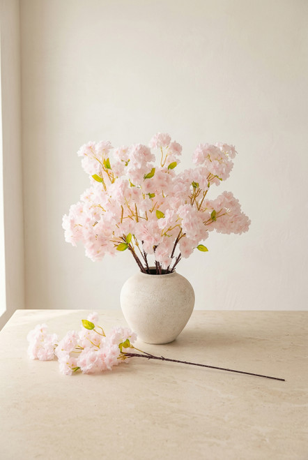 Light blush pink artificial cherry blossom branches arranged in a textured white vase with one 38 inch branch displayed on tabletop, ShopWildThings.com