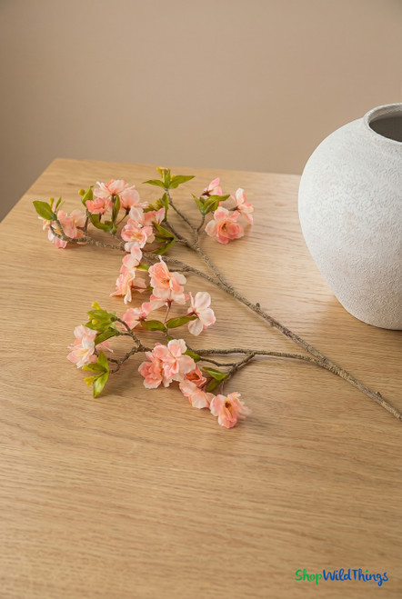 ShopWildThings artificial pink cherry blossom branch on wood table with white vase in warm minimal interior setting