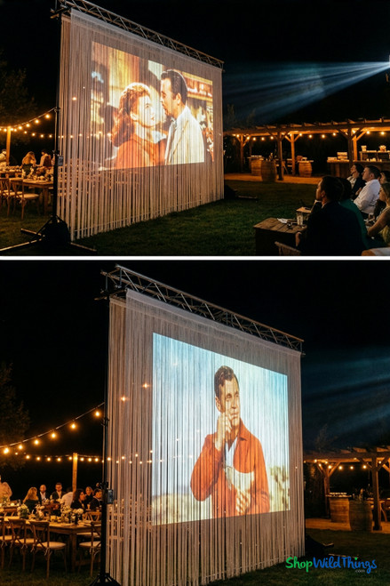 Wedding or outdoor dinner event featuring a classic movie projected onto a tall white string curtain backdrop from ShopWildThings, illuminated by warm market lights and supported by a truss frame.