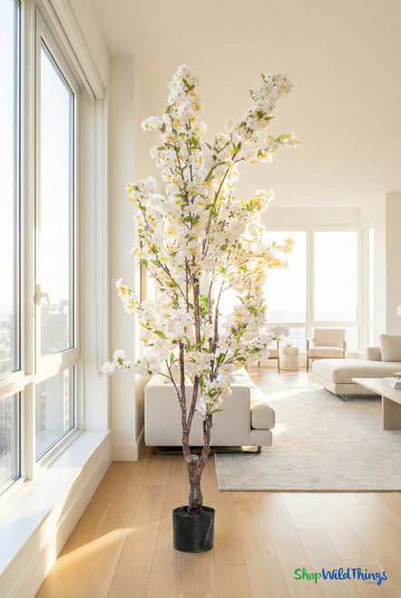 Realistic artificial white cherry blossom tree displayed indoors, featuring full blooming branches and a natural trunk for home or event décor
