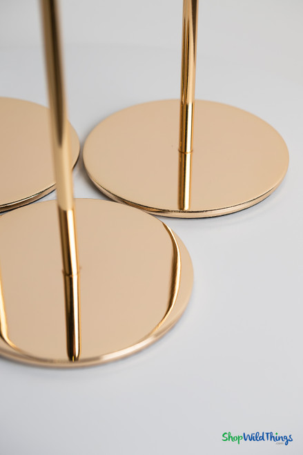 Detail of polished gold metal round bases on long stem taper candle holders providing stability for wedding and event centerpieces