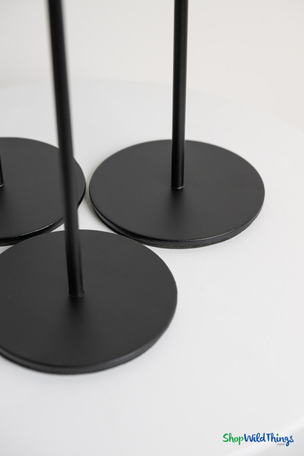 Detail of matte black round metal bases on long stem taper candle holders providing stability for wedding and event table centerpieces