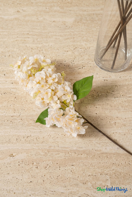 43" Deluxe Artificial Ivory Hydrangea Cone Flower Stem from ShopWildThings.com styled on a travertine table with clear glass vase for elegant event decor