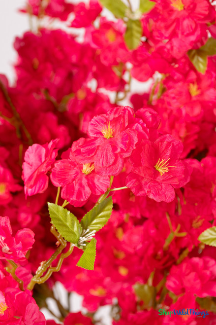 40" Artificial Fuchsia Cherry Blossom Branch – Vivid Spring Flowering Stem for Event Decor from ShopWildThings.com close up showing vivid fuchsia fabric blossoms with yellow centers and green leaves