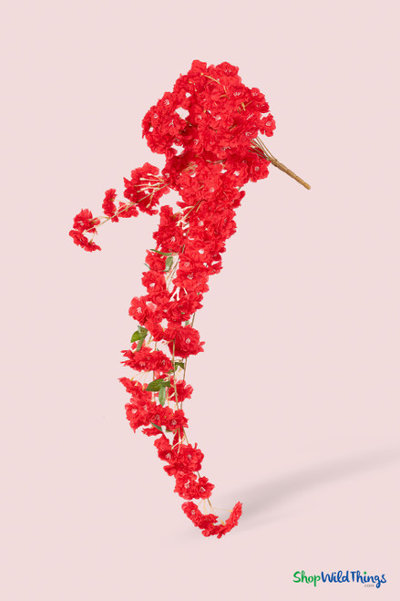 41" Red Cascading "Spring Blossom" Spray – Extra-Full Silk Floral Waterfall from ShopWildThings.com shown as a full faux floral waterfall on a soft blush background, featuring bright red blossoms, bendable brown stems, and a cascading silhouette.