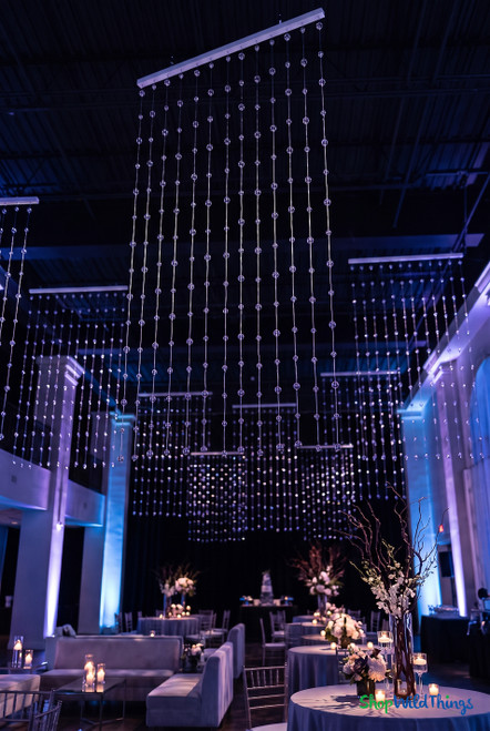 Clear Round Spheres Acrylic Ball Beaded Curtain 3' x 6' hanging in a blue-lit event venue for a sparkling ceiling installation – ShopWildThings.com
