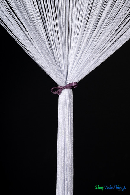 ShopWildThings White String Curtain tied at the center with a purple ribbon bow for a chic, decorative look suitable for weddings, displays, or boutique entrances.