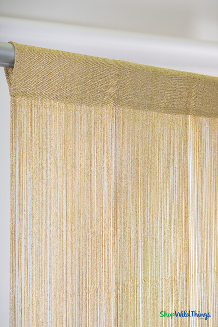 Gold metallic string curtain panel with shimmer strands and rod pocket header close-up on curtain rod – ShopWildThings.com
