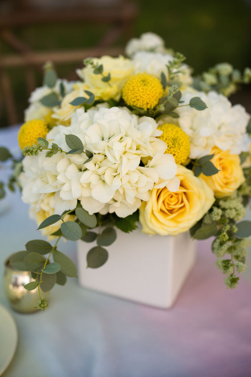 Spring Centerpiece with White Hydrangea and Billy Balls White hydrangea meets yellow billy balls and yellow roses in a chic White Cube Vase for a simple, budget-friendly centerpiece with bold color impact.