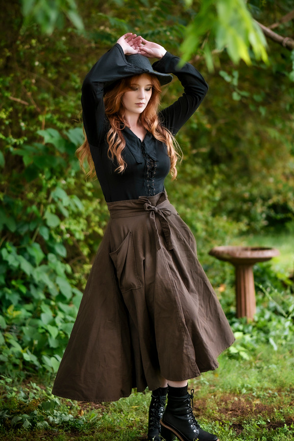 Forager Skirt in Olive Brown, front view with hands up and twirling Forager Skirt in Olive Brown, front view with hands up and twirling