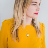 woman in yellow blouse looking away from camera wearing silver stacy locket