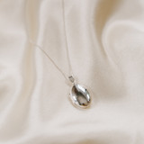 oval shaped locket necklace on cream silk backdrop
