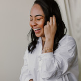 woman in white shirt with hands by her hair showing custom locket pendants dangling on bangle bracelet