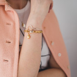 spring look with pink coat, gold and silver bangle charm bracelets, and gold charm bracelet 