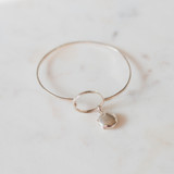 silver bangle bracelet holds one or two photos on a white marble table