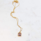 Gold open square locket with gold chain, laying on marble table