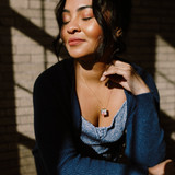 modern locket necklace modeled by woman standing in sunlight