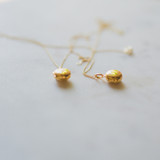 two gold edith lockets, small round pendants with pictures inside, on white marble