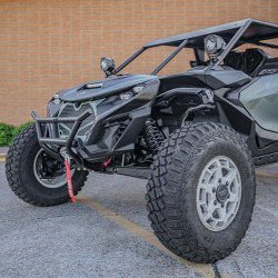 2026 Can-Am Maverick R, green and black side-by-side off-road vehicle shown from the front side with rugged tires, roll cage, and front bumper