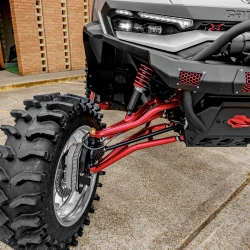 2026 Can-Am Defender HD11, close-up of the silver, red, and black off-road side-by-side showing its front suspension, large rugged tire, LED headlight, and red accents.