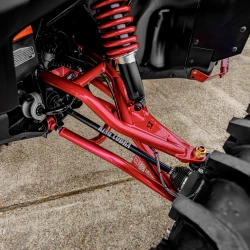 2026 Can-Am Defender HD11, close-up of the red front suspension, coil-over shock, and control arms beneath the black bodywork.
