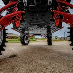2026 Can-Am Defender HD11, Silver / Red / Black, underside view showing black protective skid plates, red suspension components, and rugged off-road tires