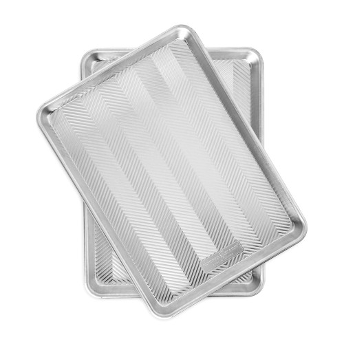 Two Nordic Ware aluminum half sheet pans stacked, rectangular with raised rims, natural silver finish