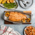 naturals fish and seafood griller with salmon on cutting board  with plated corncobs, asparagus, and shrimp