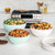 Nordic Ware 3 piece seaglass and white 5 quart, 3.5 quart and 2 quart bowls filled with salad, potatoes and mixed nuts on a countertop