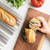 hand holding up half of baguette sandwich on cutting board with loaf nested in Nordic Ware baguette & french bread pan