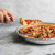 hand using server to lift a slice of pizza from deep dish pizza pan